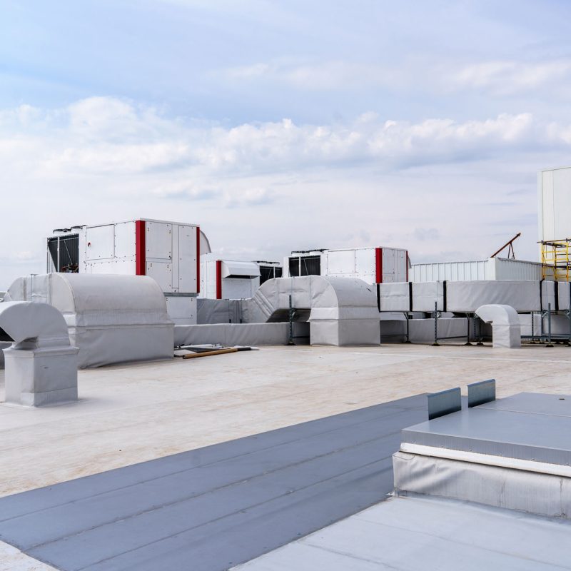 The air conditioning and ventilation system of a large industrial building is located on the roof. It consists of air ducts, air conditioning, smoke removal and ventilation